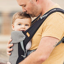 father figure wearing a young boy in a black beco gemini carrier on his front and kissing his head