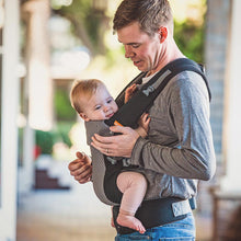 a father wearing a young girl on his front in a cool mesh beco carrier with crossed straps