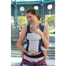 a mother wearing a young boy in a cool mesh navy beco carrier with crossed straps outside
