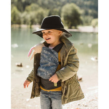 young child carrying a toy bunny in a doll carrier
