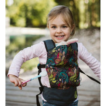 young child wearing a doll carrier with a toy bunny