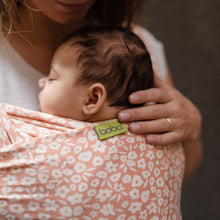 a parent with a newborn baby wrapped snuggled close to their chest