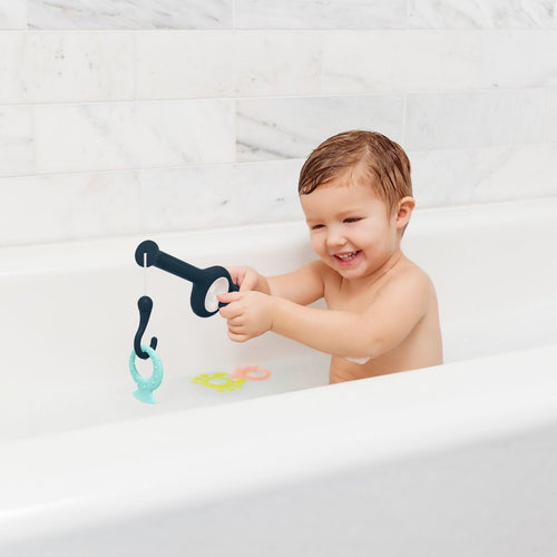 Baby in the bath playing with the boon cast fishing rod and three floating shapes