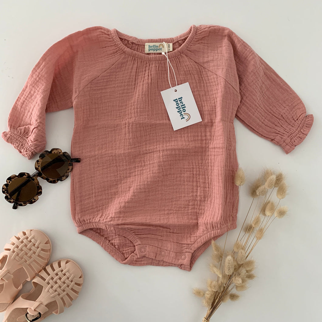 a deep dusky pink with long sleeve bodysuit with elastic around the legs and domes for nappy changes, small frill around the cuff