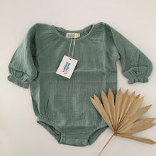 a deep sage green with long sleeve bodysuit with elastic around the legs and domes for nappy changes, small frill around the cuff