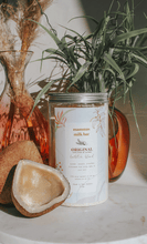 half a coconut sitting next to a large jar of lactation blend with plants in vases behind