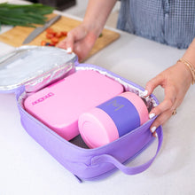 purple insulated lunch bag unzipped with a pink yumbox showing an original and pink and purple food jar both fit, wooden chopping board with knife and chopped fruit in the background