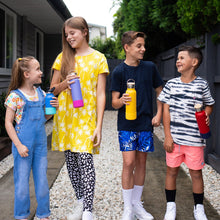 four children standing outside in a driveway all holding drink bottles with bumpers