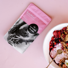 a smoothie breakfast bowl with yoghurt, nuts, fresh berries, pansy with a mix sprinkled on it