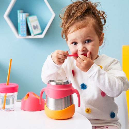 Young girl eating food from a b.box strawberry shake insulated food jar